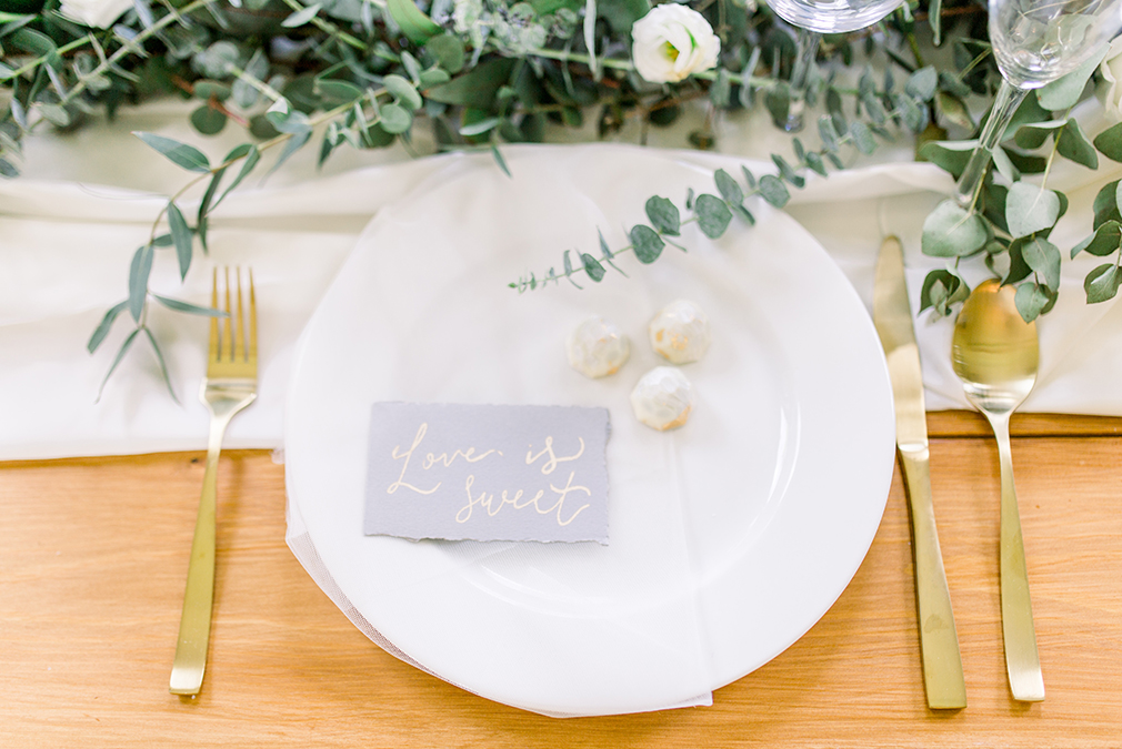 A table setting is dressed with gold cutlery and grey stationery for an elegant wedding breakfast set up at Braxted Park