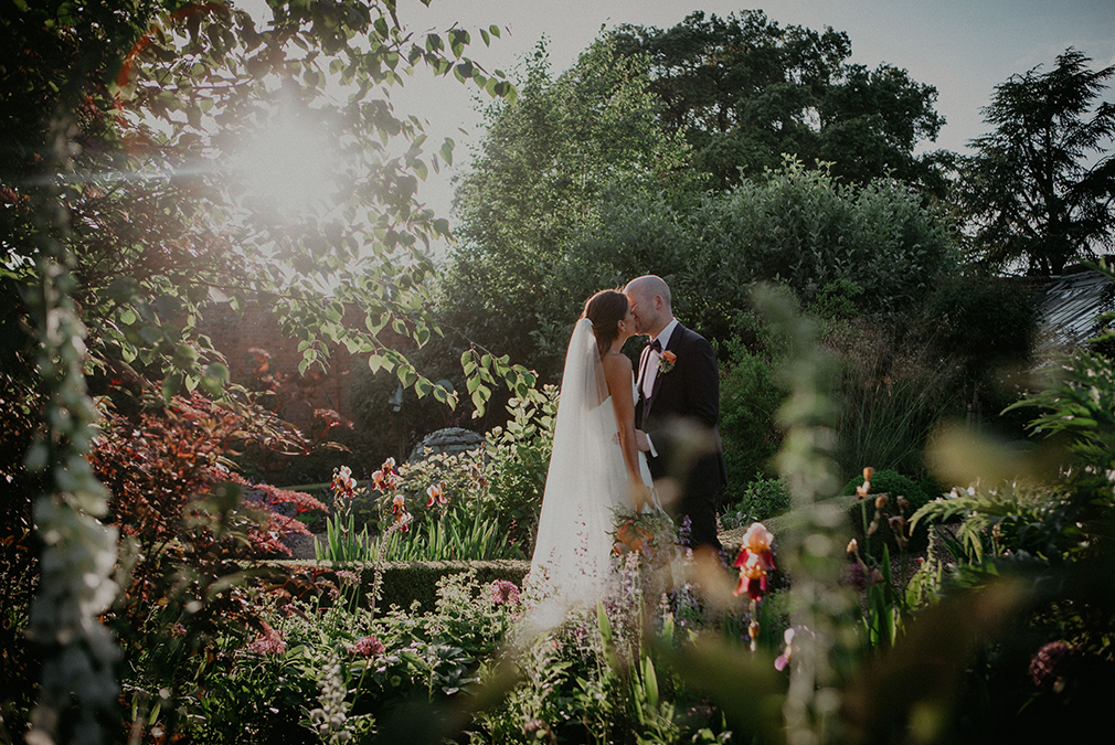 Newlyweds share a kiss in the Walled Gardens on their wedding day at Braxted Park in Essex