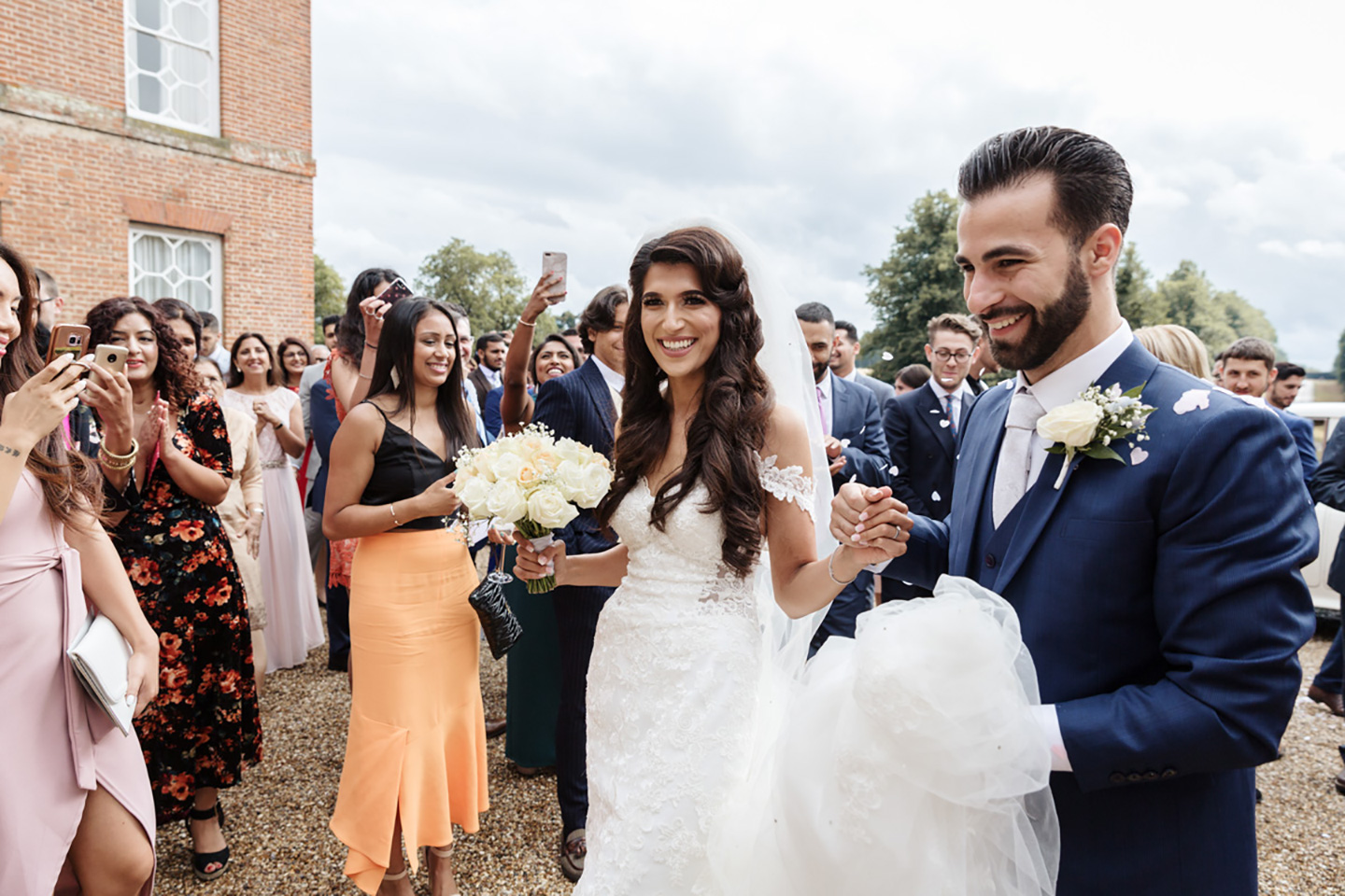 Newlyweds are greeted by guests for their Asian wedding reception at Braxted Park in Essex