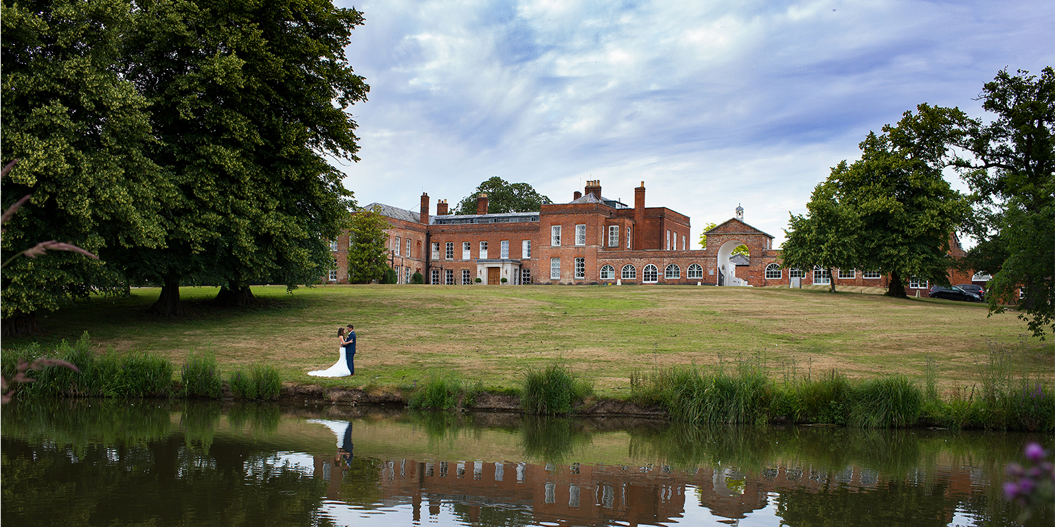 The bride and groom take a walk around the grounds at Braxted Park on their summer wedding day